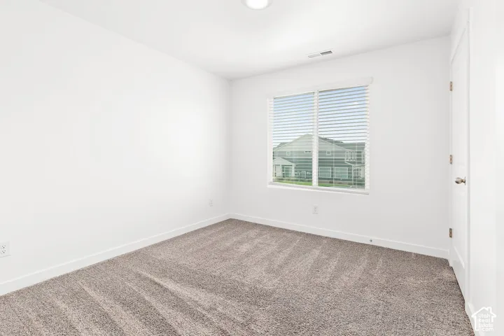 Neutral wall color, carpeted flooring, window with blinds, recessed ceiling light