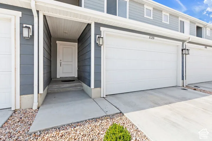 Siding exterior with white trim, a covered entryway, and an attached garage