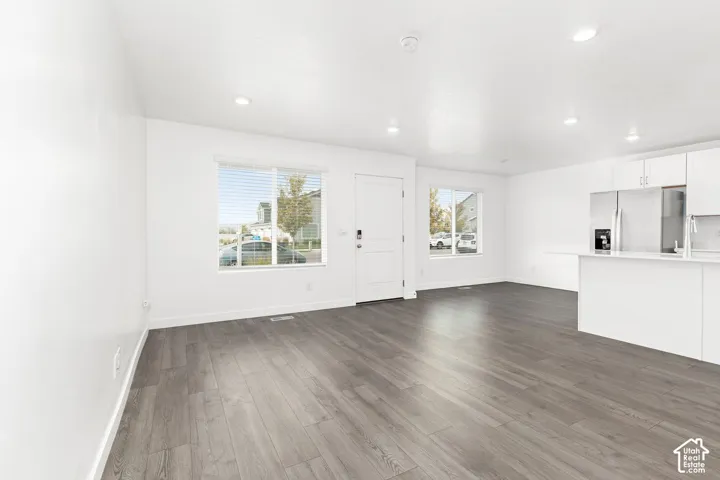Open-concept living space featuring recessed lighting, wood-finish flooring, and two large windows