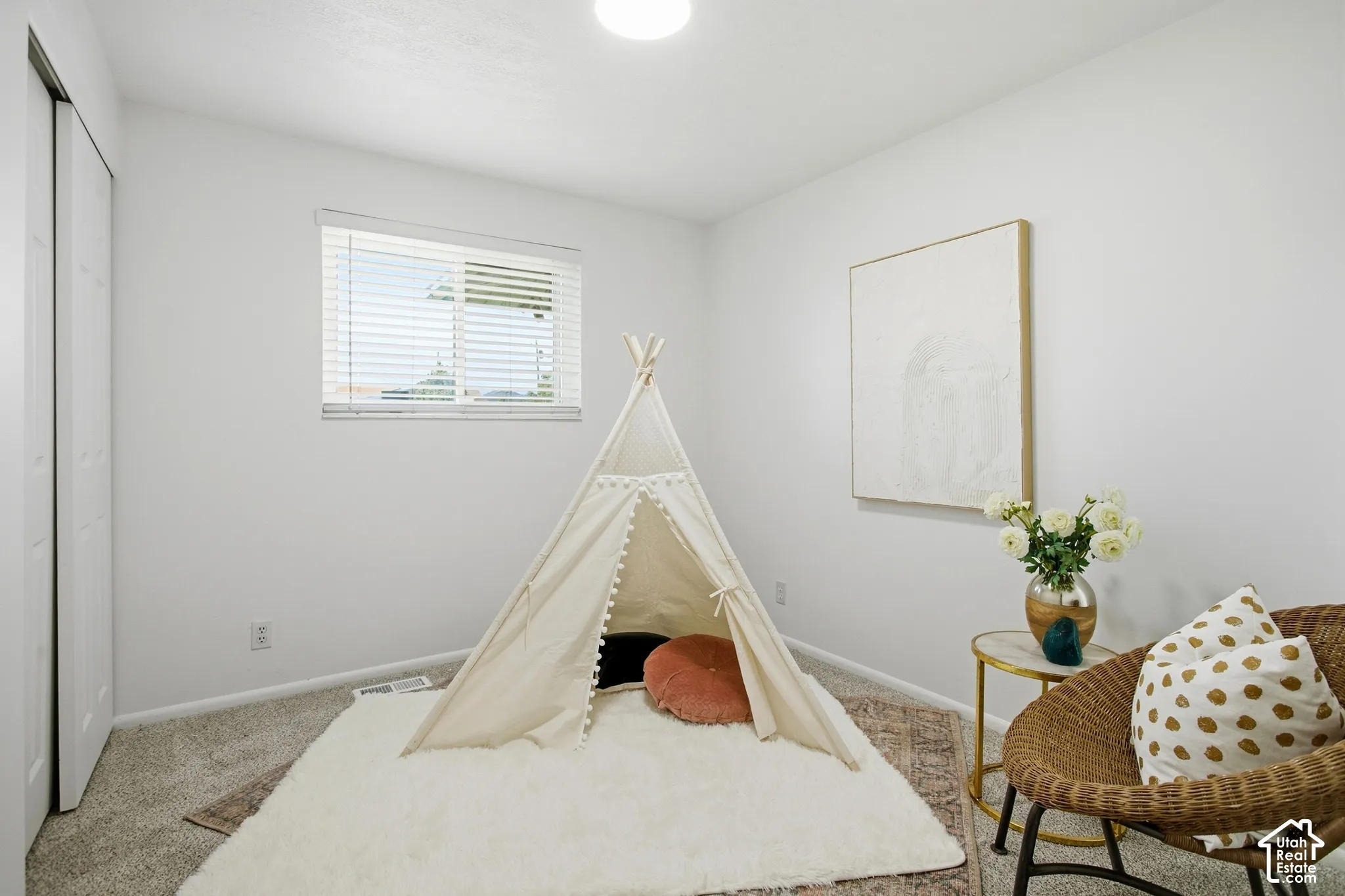 Recessed lighting and a window with horizontal blinds illuminate this room featuring carpeted flooring and white walls