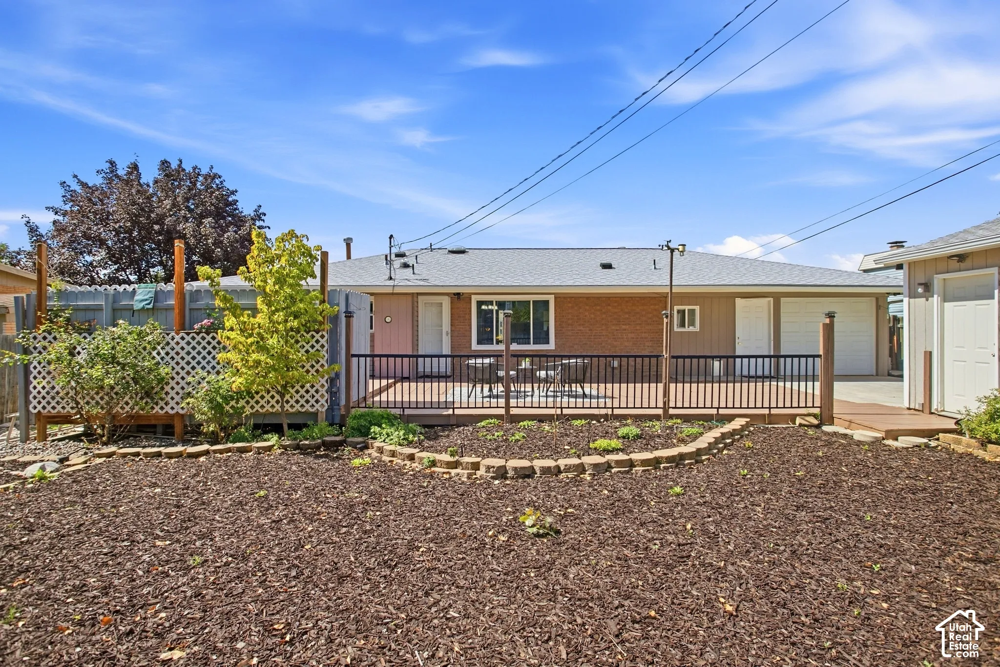 Expansive backyard featuring a wood-finish deck with black railing, a brick-finish exterior, and a detached structure
