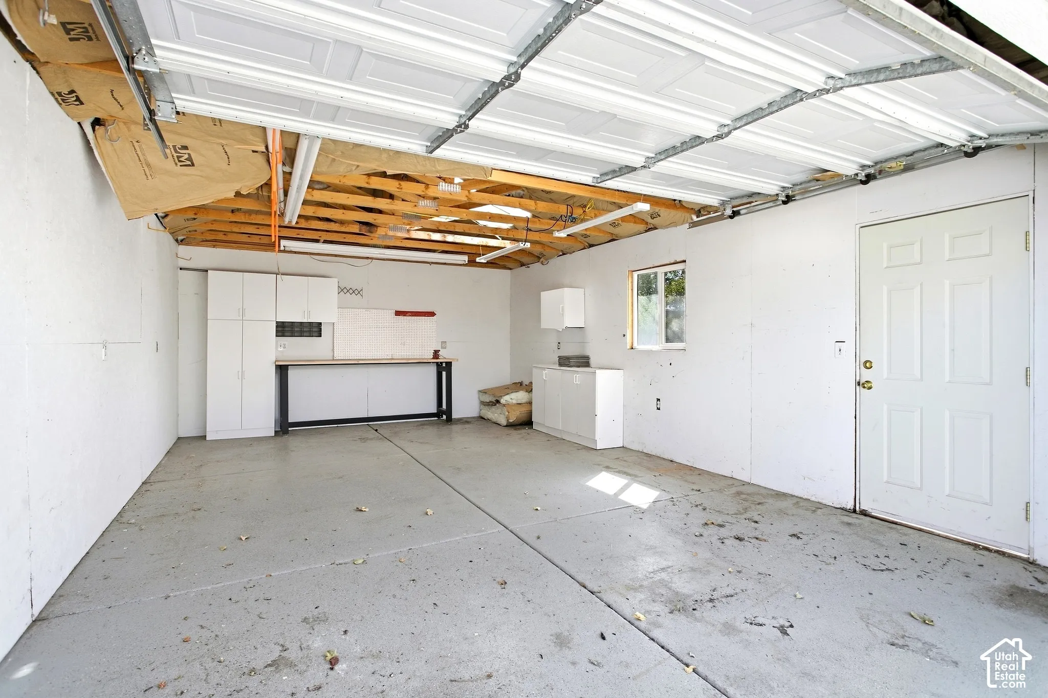 Spacious detached garage with concrete flooring, built-in cabinetry, an integrated workbench, and a white paneled door