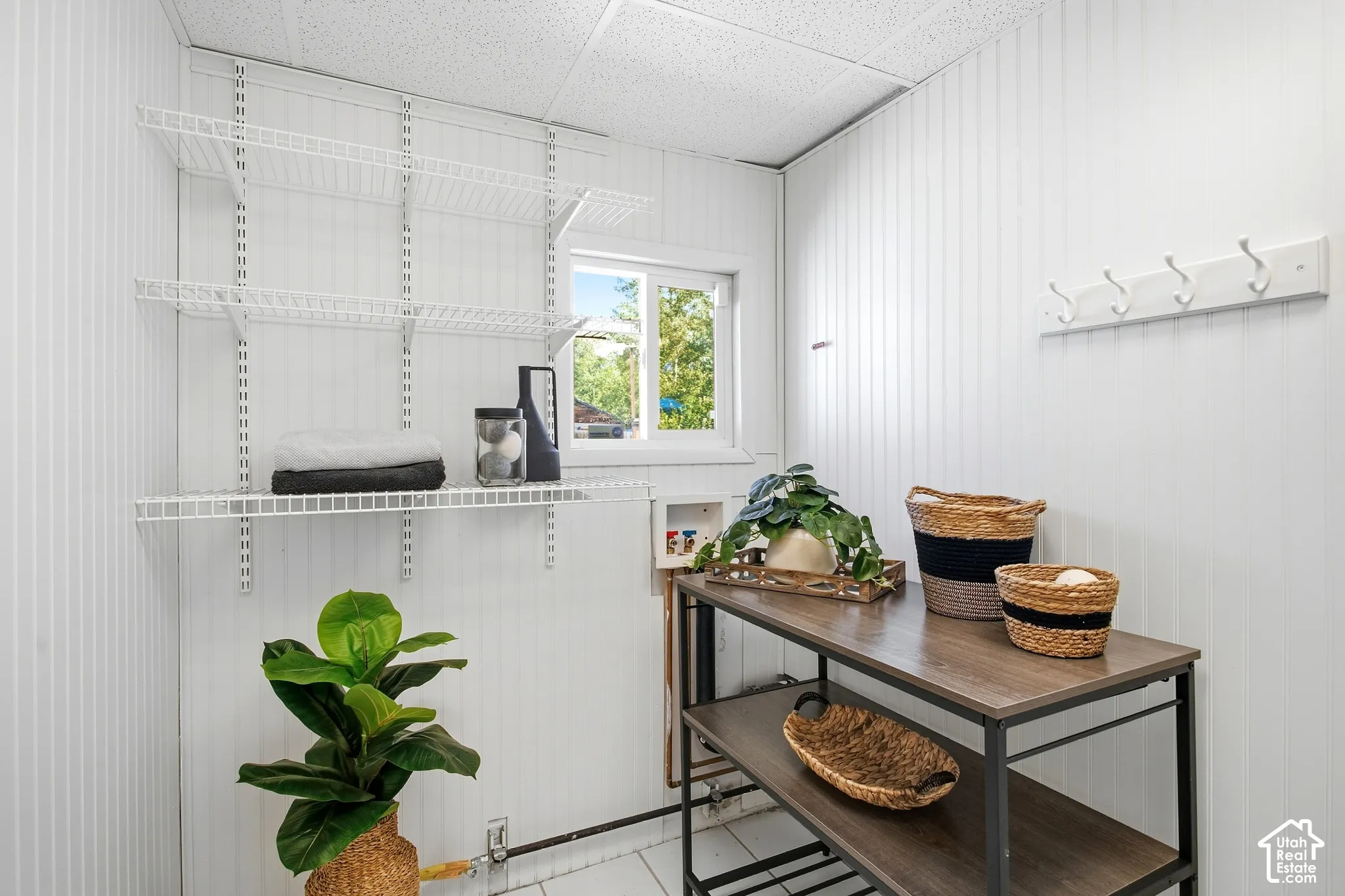 Vertical paneled wall cladding, white wire shelving system, built-in window, dark wood-finish open shelving unit, white ceiling panels