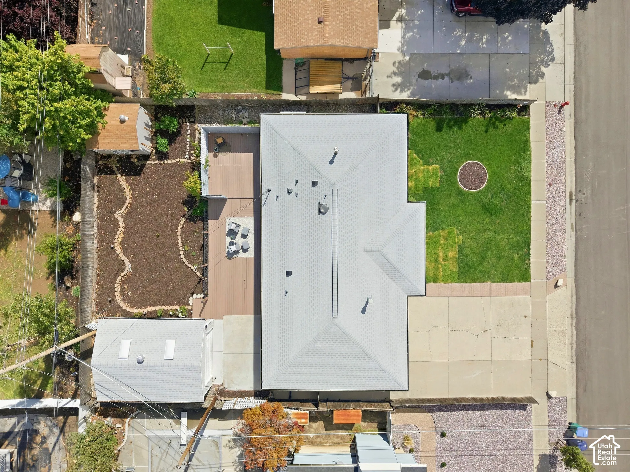 Expansive rear deck, detached garage, front yard with green lawn, gravel landscaping, and concrete driveway