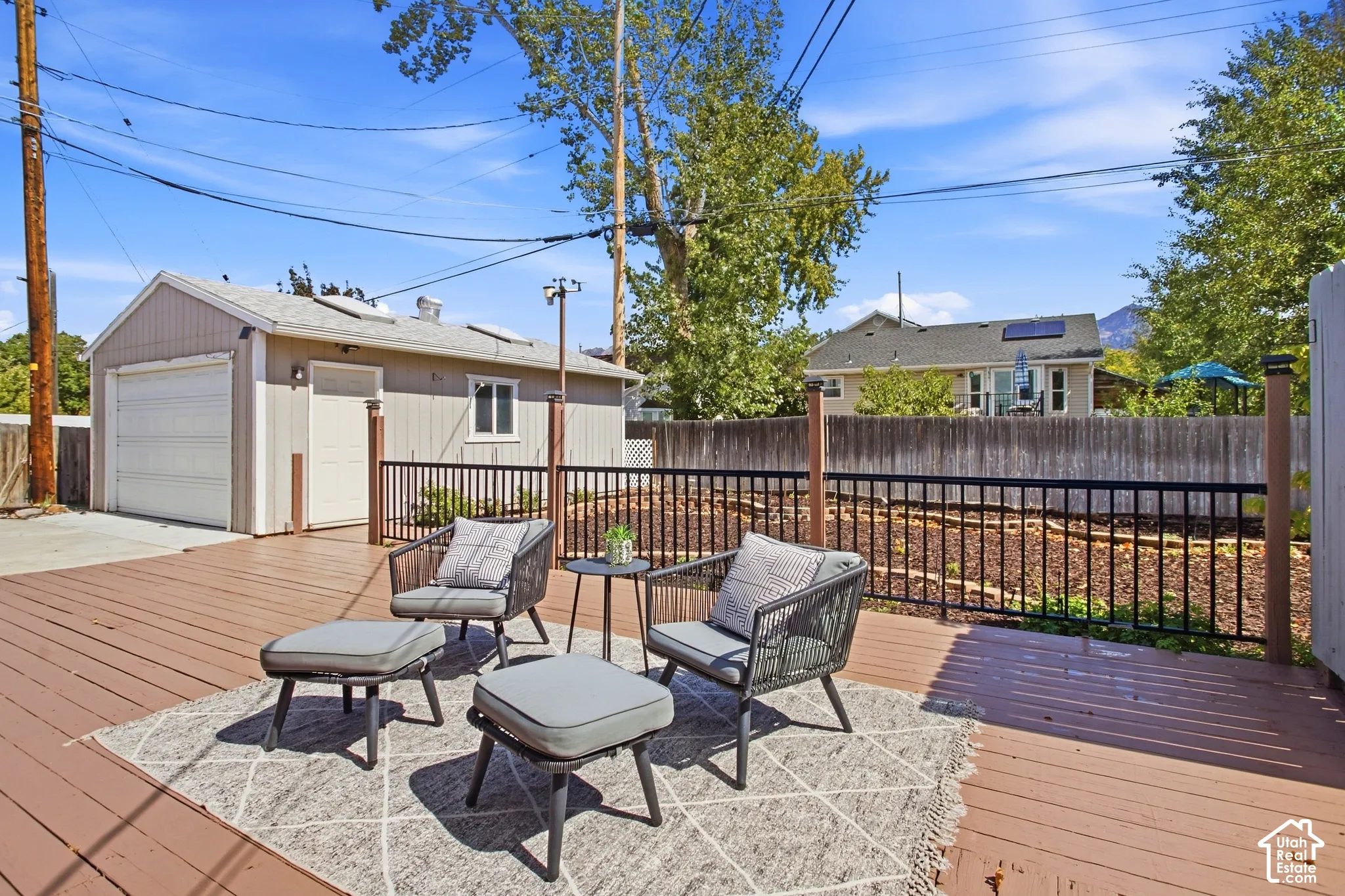 Back of home with peek a boo mountain views, Expansive outdoor deck with wood-finish planks and a black metal railing