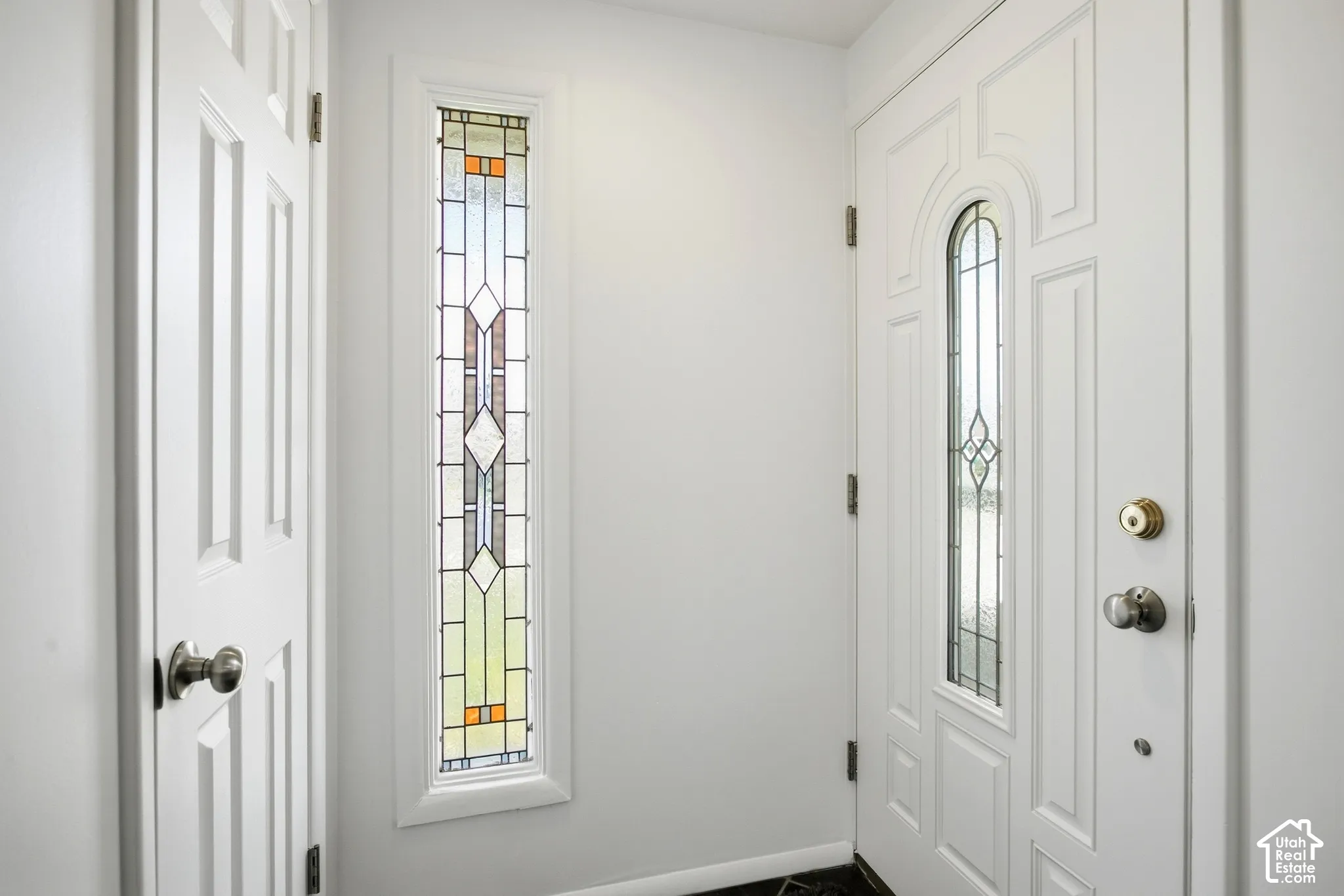 White paneled door with decorative glass inlay and polished brass hardware