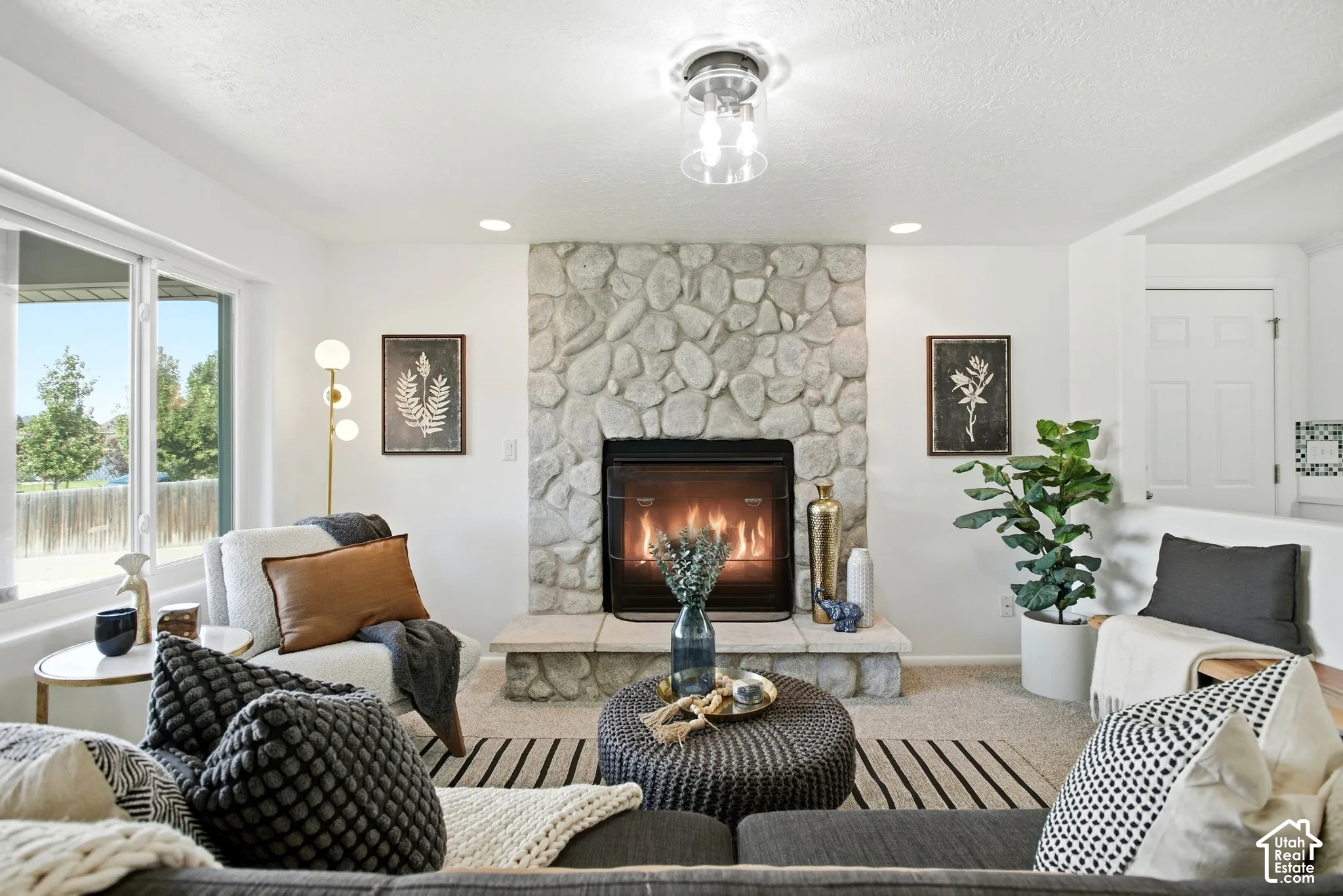 Stone-clad fireplace with a raised hearth, large window with ample natural light, recessed lighting, and a contemporary ceiling light fixture