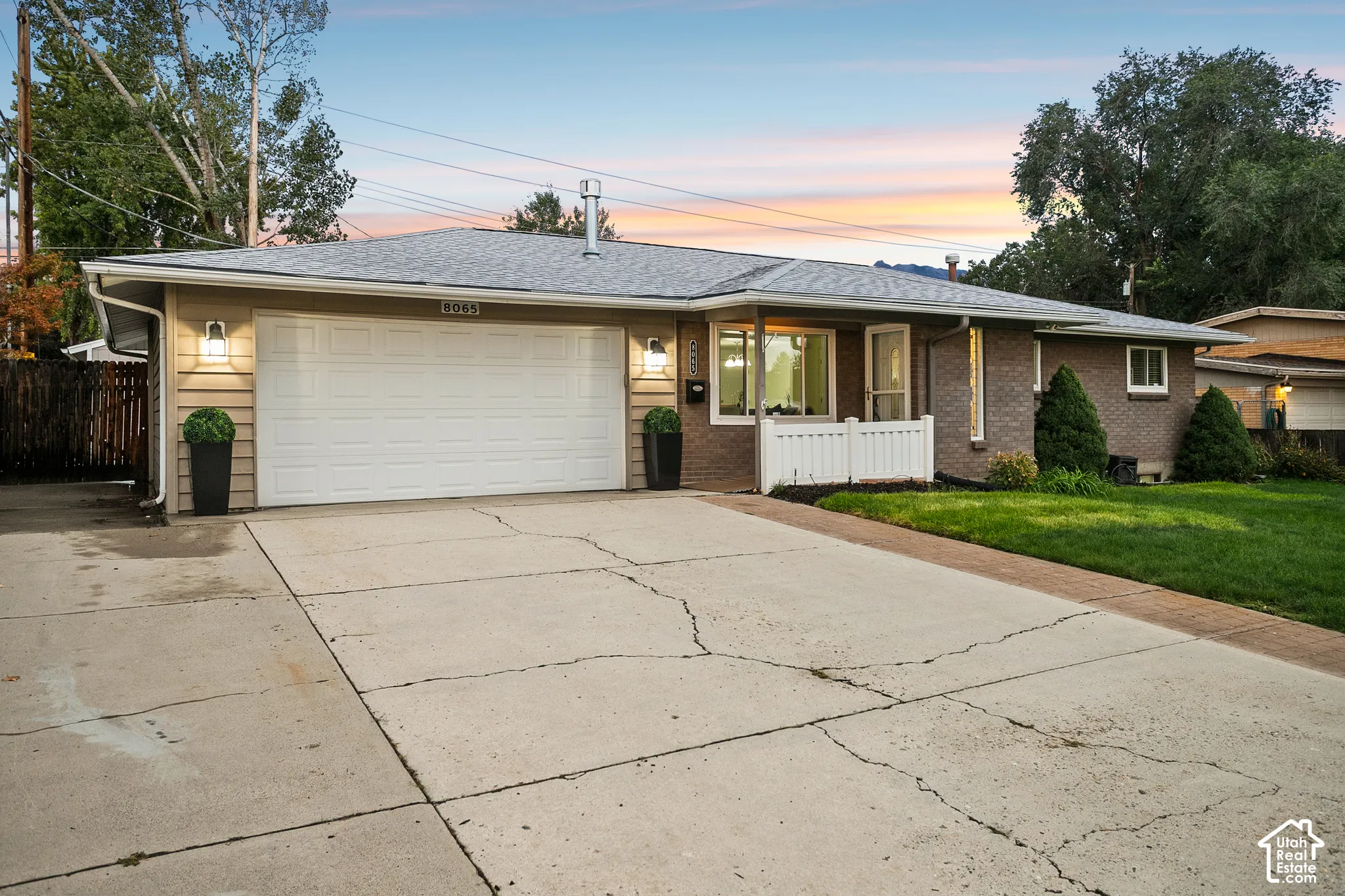 Brick and siding exterior with a white garage door, concrete driveway, and front lawn