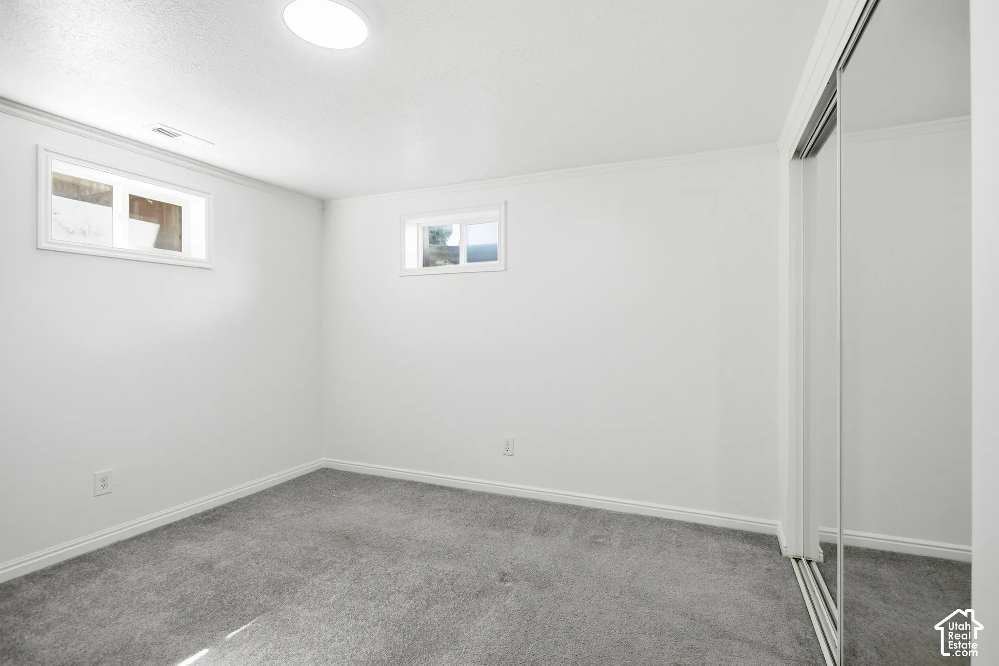 Bright interior with recessed lighting, two windows, carpet flooring, and a mirrored closet