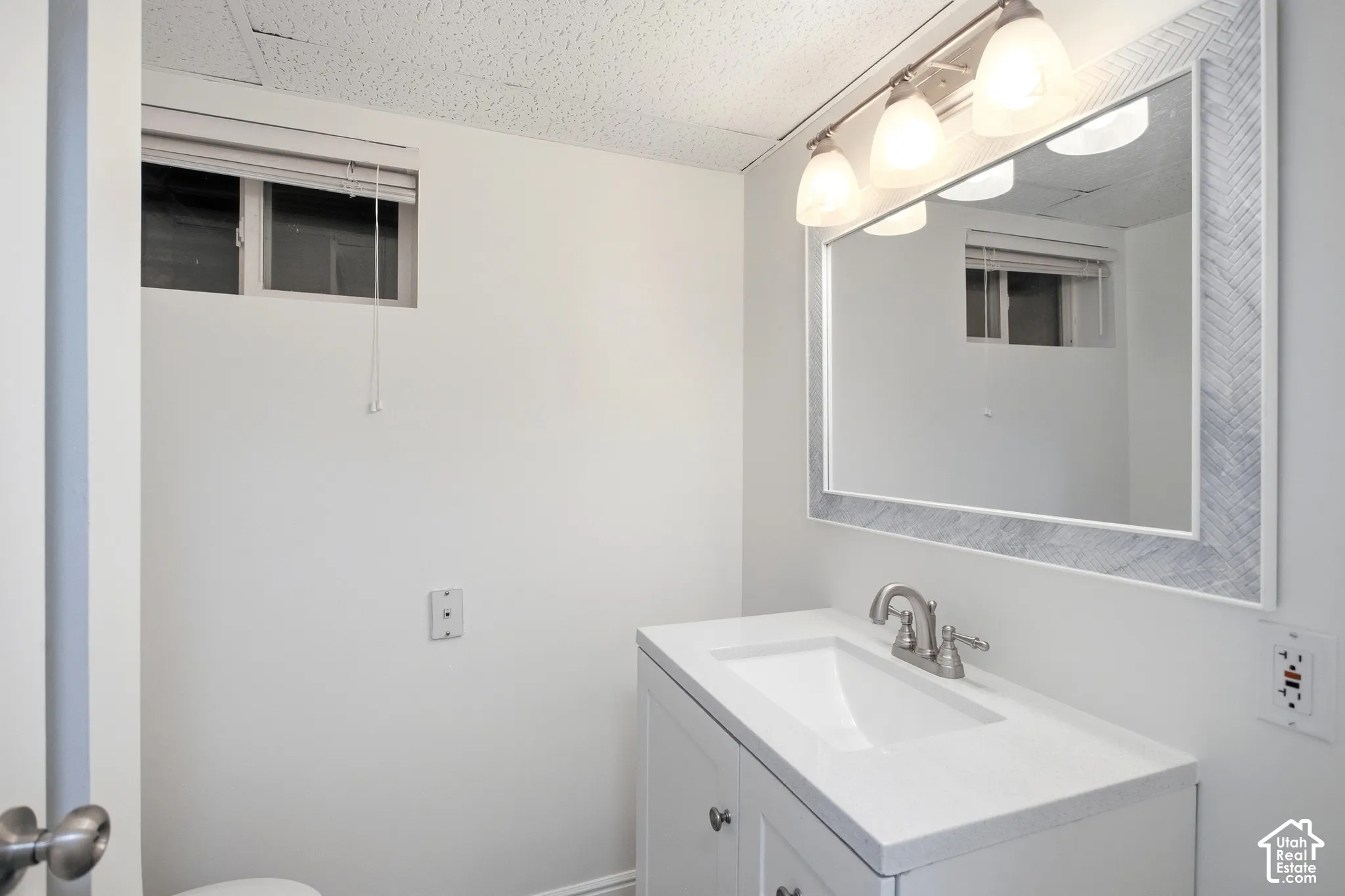 3/4 Bathroom featuring a single vanity with a white countertop, wall-mounted mirror with a decorative frame, and overhead lighting