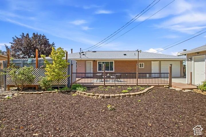 Expansive backyard featuring a wood-finish deck with black railing, a brick-finish exterior, and a detached structure
