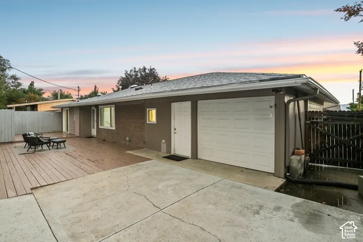 Exterior featuring a multi-panel attached garage, wood siding, and a spacious outdoor deck