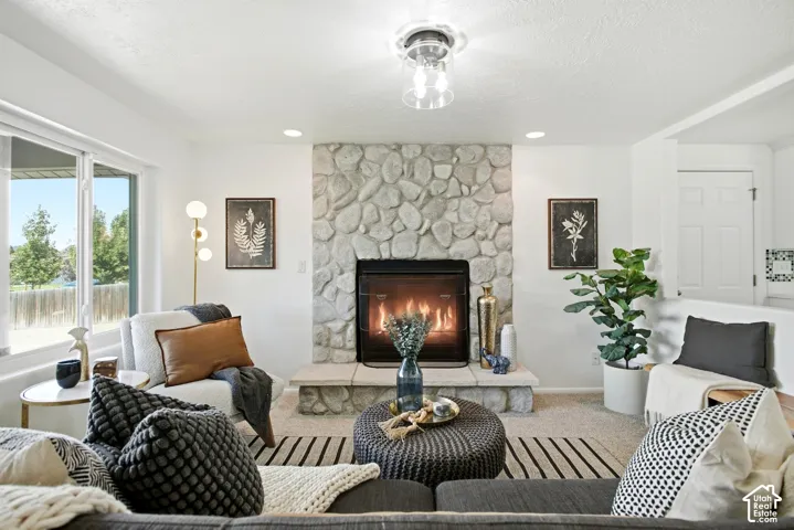 Stone-clad fireplace with a raised hearth, large window with ample natural light, recessed lighting, and a contemporary ceiling light fixture