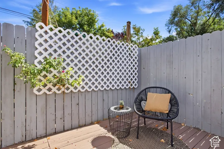Private outdoor deck off of primary suite featuring wood-finish decking and privacy fence