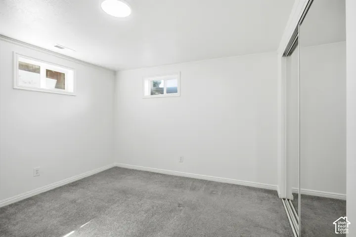 Bright interior with recessed lighting, two windows, carpet flooring, and a mirrored closet