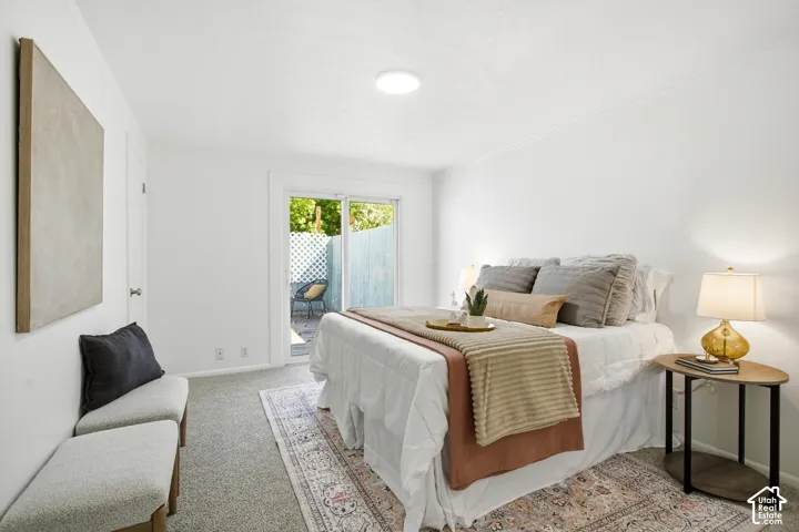 Primary Bedroom with White walls, gray carpet, and a sliding glass door leading to an outdoor area with a white lattice fence