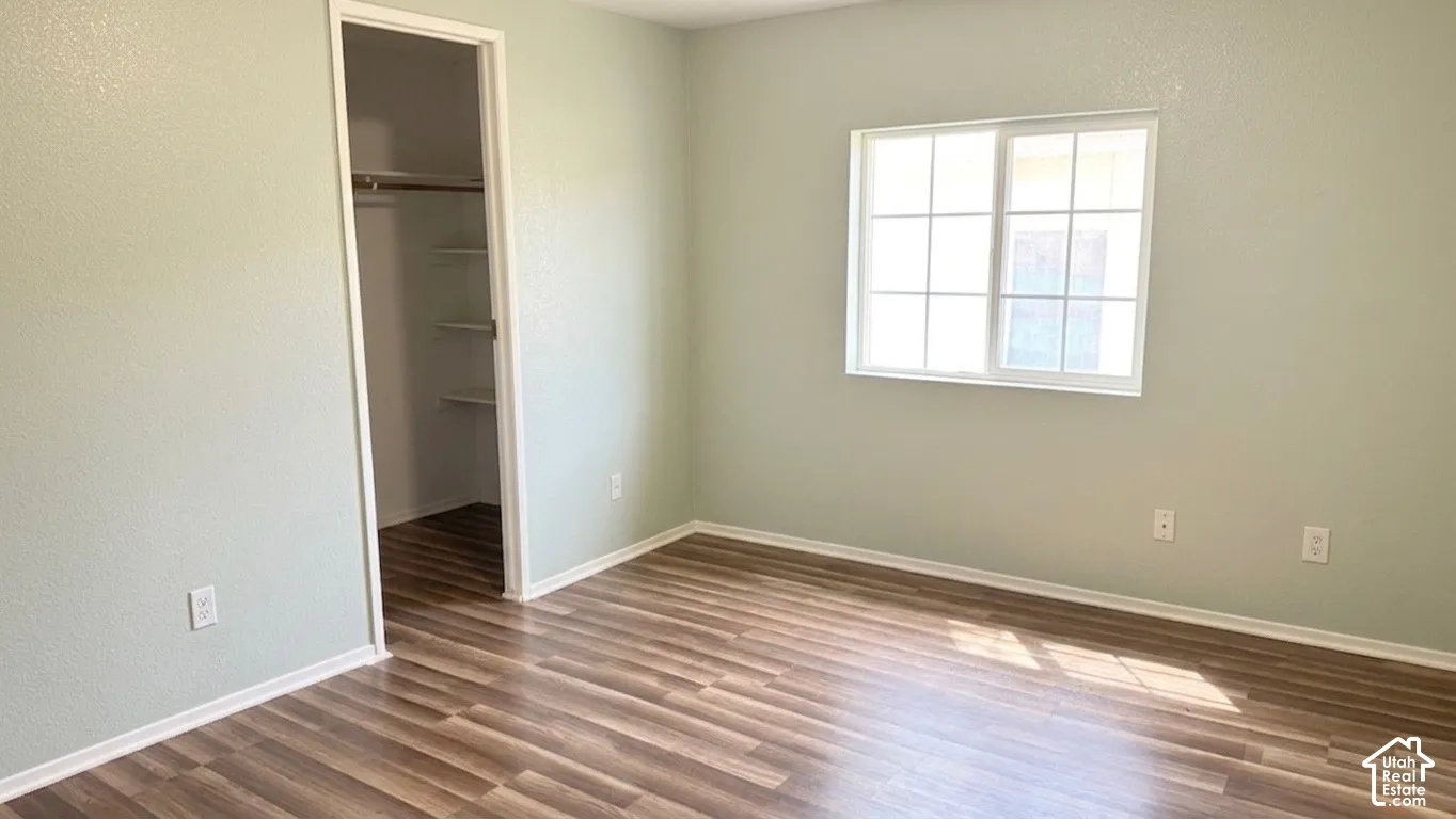 Wood-finish flooring, light-colored walls, window with grilles, and a closet with shelving and a hanging rod