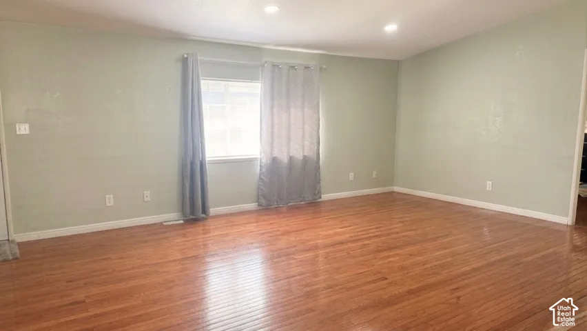 Spacious room featuring wood-finish flooring, recessed lighting, and a window with natural light