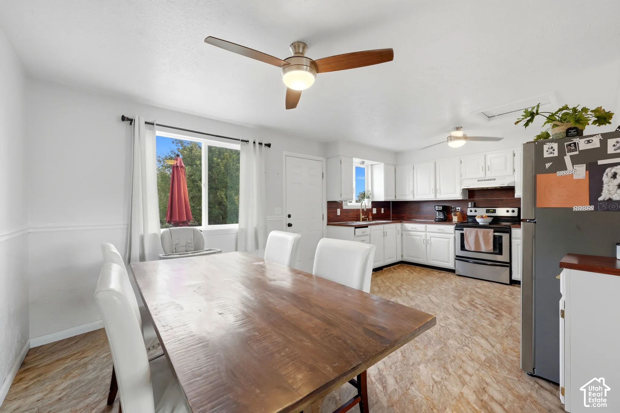 White cabinetry kitchen featuring a stainless steel range, a stainless steel refrigerator, and wood-finish flooring