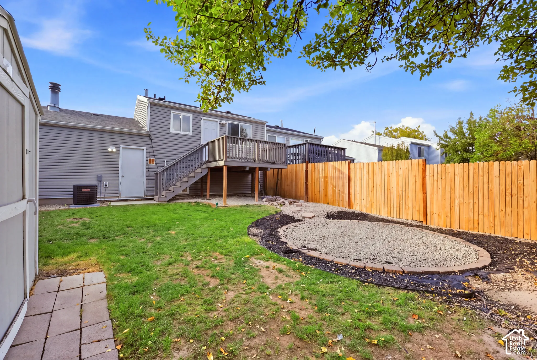 Expansive backyard featuring a wood privacy fence, a multi-level deck, and a defined gravel area