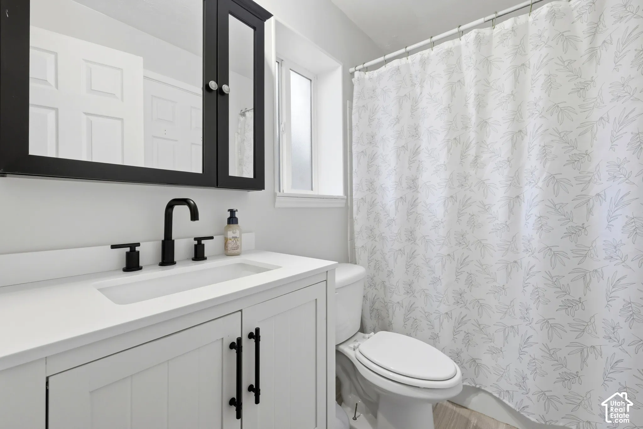 White vanity with panel-style doors and matte black hardware