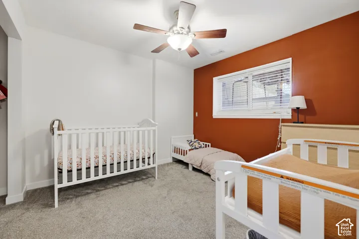 Neutral-toned wall with a single accent wall, window with blinds, and ceiling fan with integrated lighting