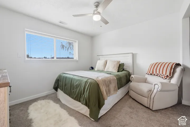 Large window with blinds, ceiling fan with integrated lighting, and carpeted flooring