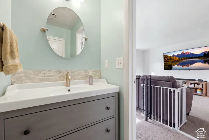 Vanity featuring an integrated sink, brushed nickel faucet, and a tiled backsplash