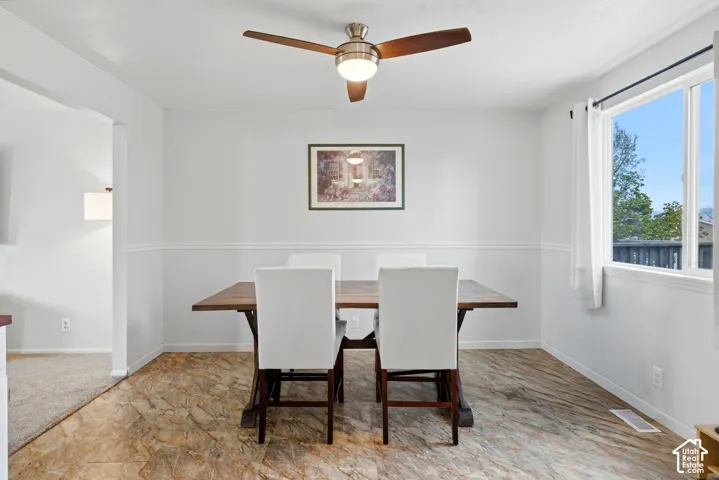 Dining area featuring wood-finish flooring, a ceiling fan with integrated lighting, and a large window