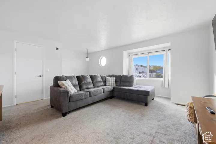 Carpeted flooring, white walls, bay window, round accent window, and a single pendant light fixture