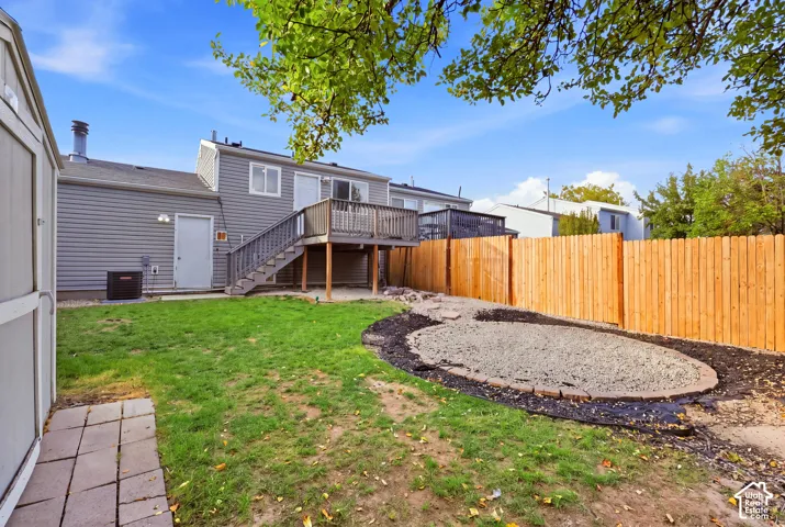 Expansive backyard featuring a wood privacy fence, a multi-level deck, and a defined gravel area