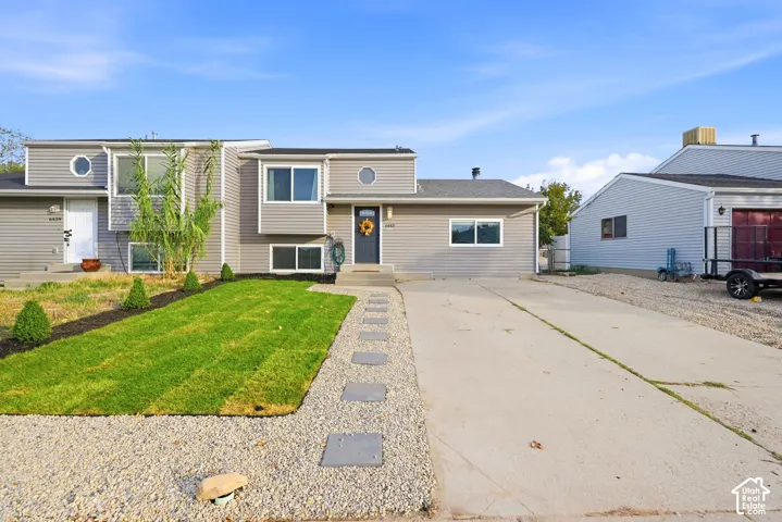 Split-level exterior with light gray siding, a dark blue entry door, and a concrete driveway