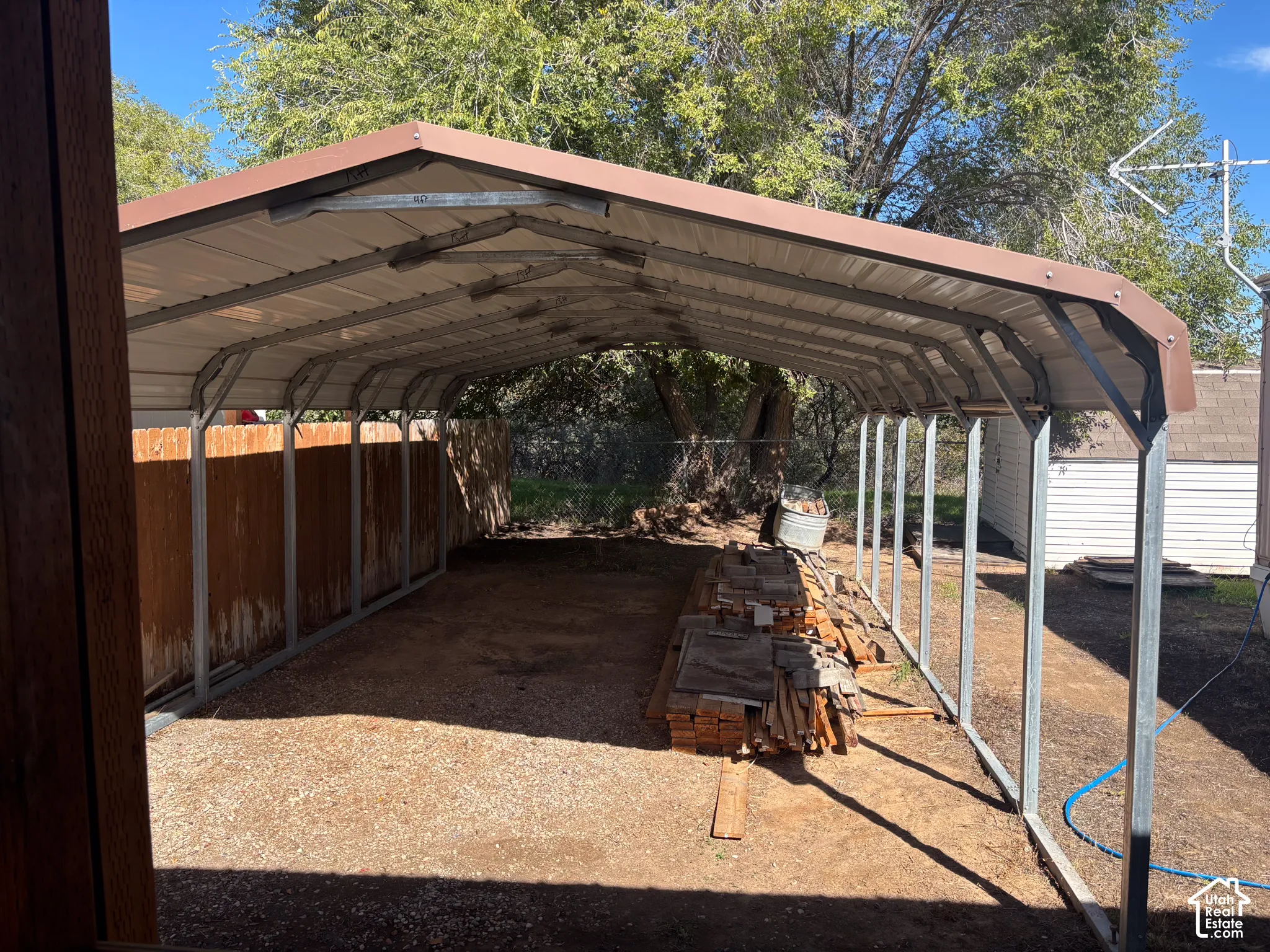 Covered carport structure with a metal roof and gravel flooring