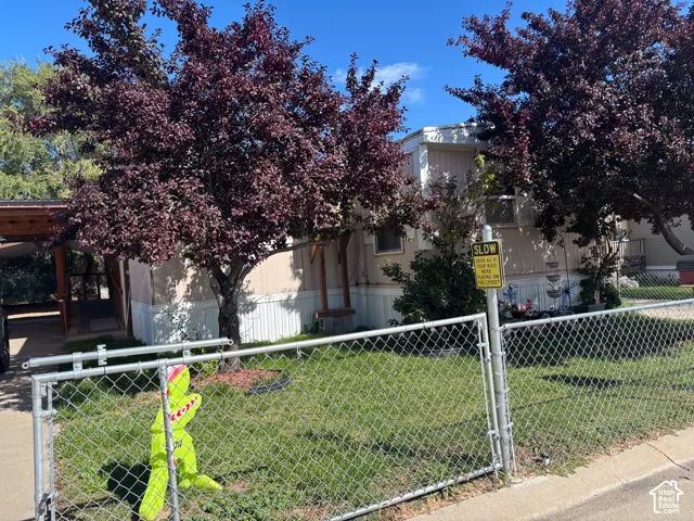 Chain link fence surrounding a grassy area with mature trees and a covered entry
