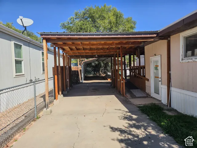 Covered carport structure with a concrete driveway, wood support beams, and a metal roof