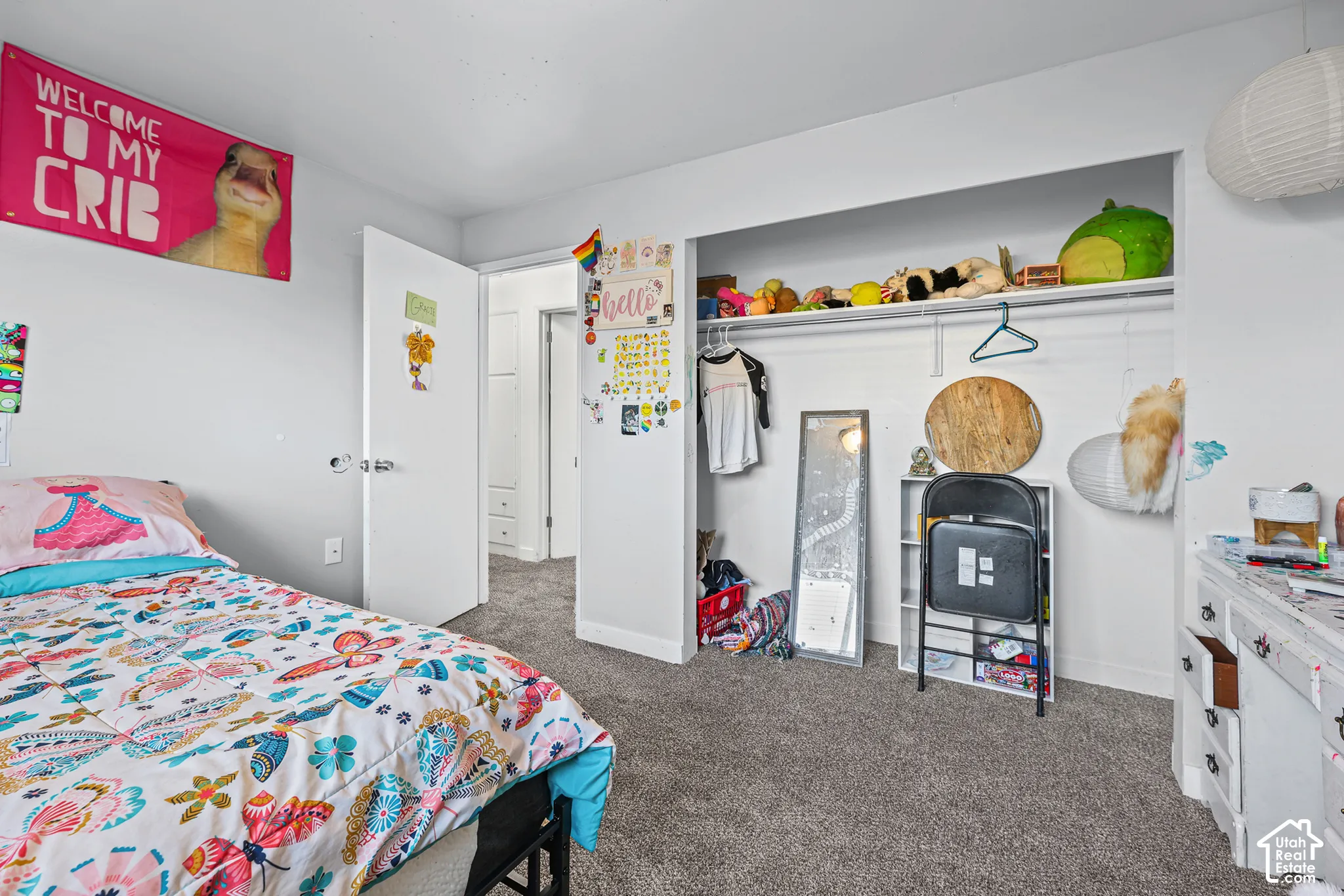 Wall-to-wall carpeting in a neutral tone, white painted walls, and a built-in closet with shelving and hanging space
