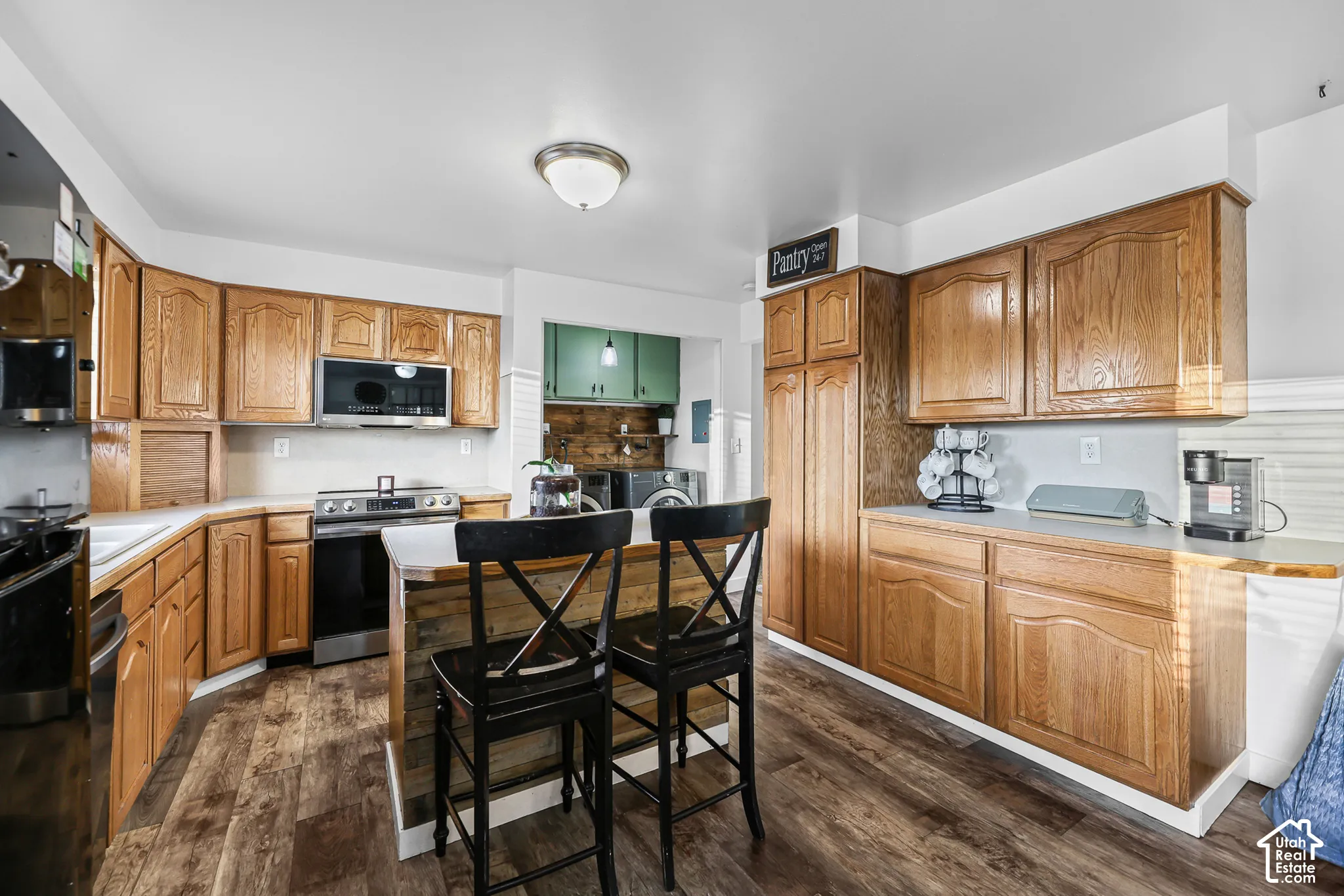 Wood-finish flooring, wood cabinetry, stainless steel range and microwave, and a central island with countertop