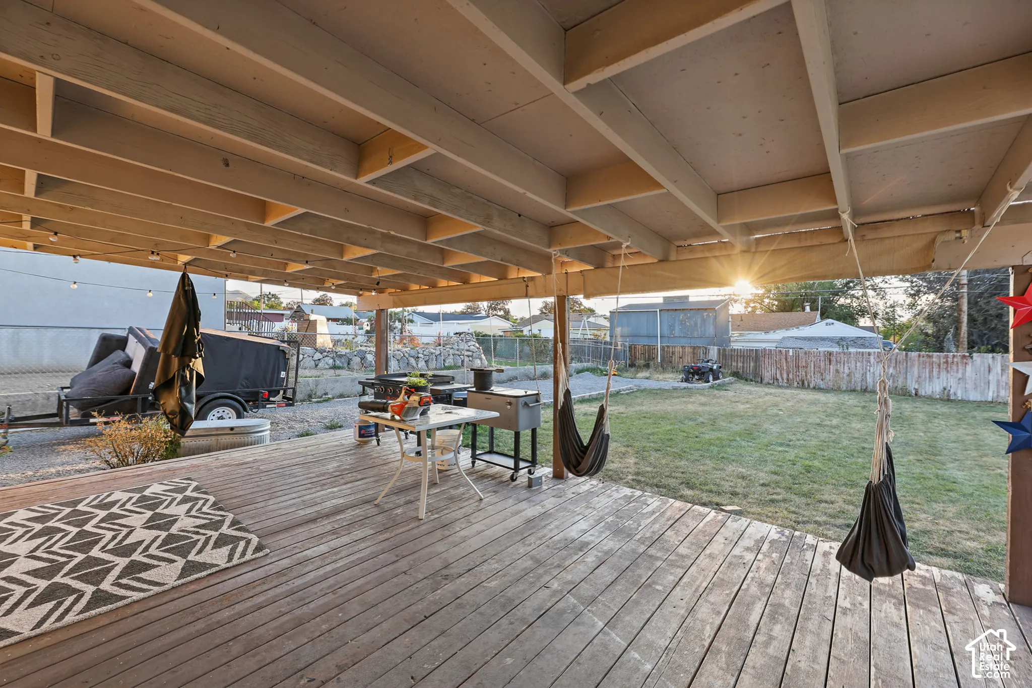 Expansive covered deck with exposed beam ceiling, string lighting, and wood-finish decking