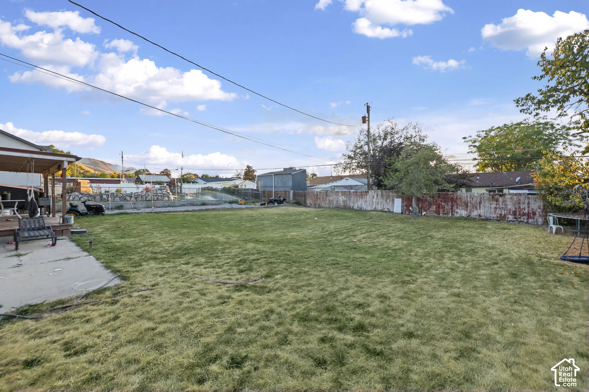 Expansive grassy yard with a concrete patio and a covered porch