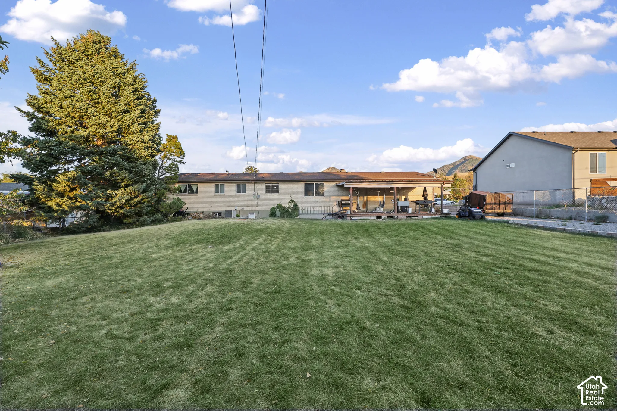 Expansive lawn with mature trees and a covered patio with a wood deck