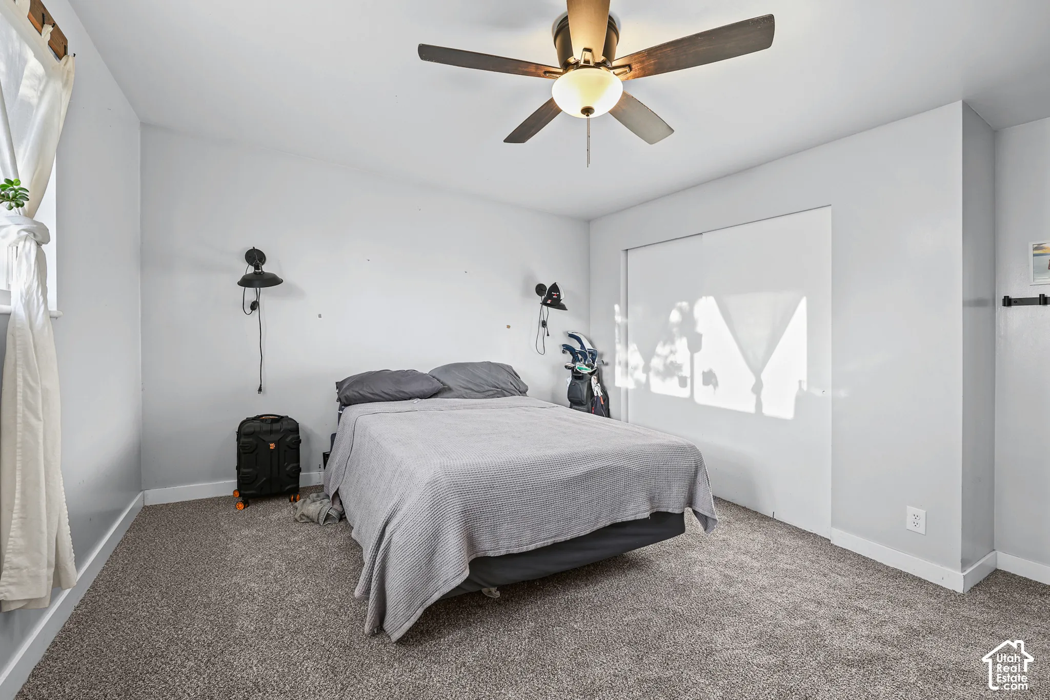 Neutral-toned wall paint, textured carpeting, and a ceiling fan with integrated lighting