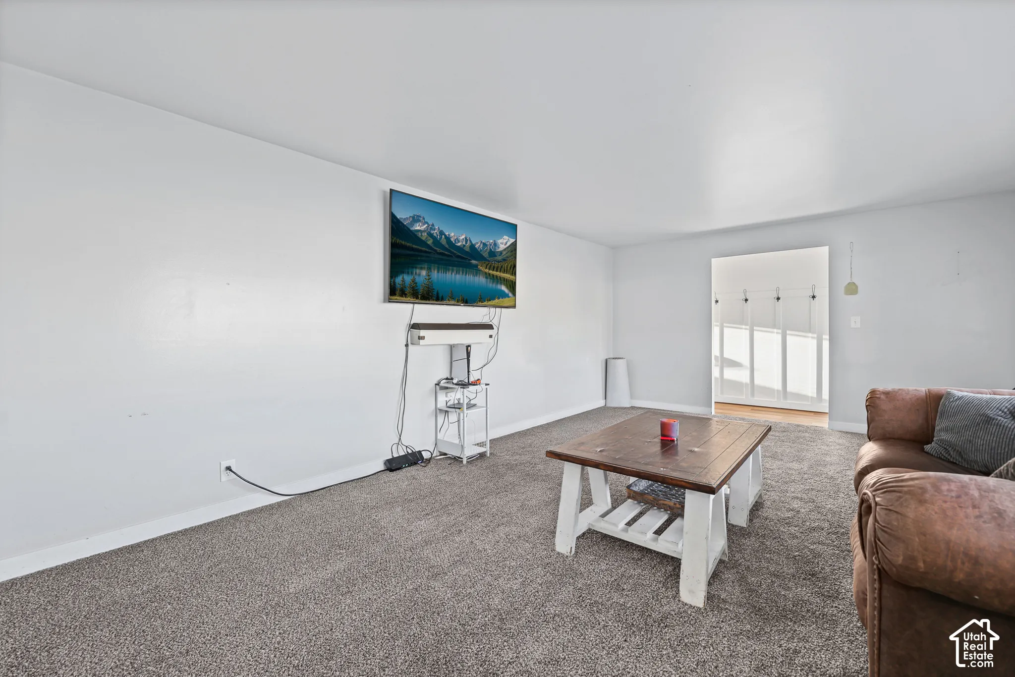 Carpeted living area with white walls and a wide entryway