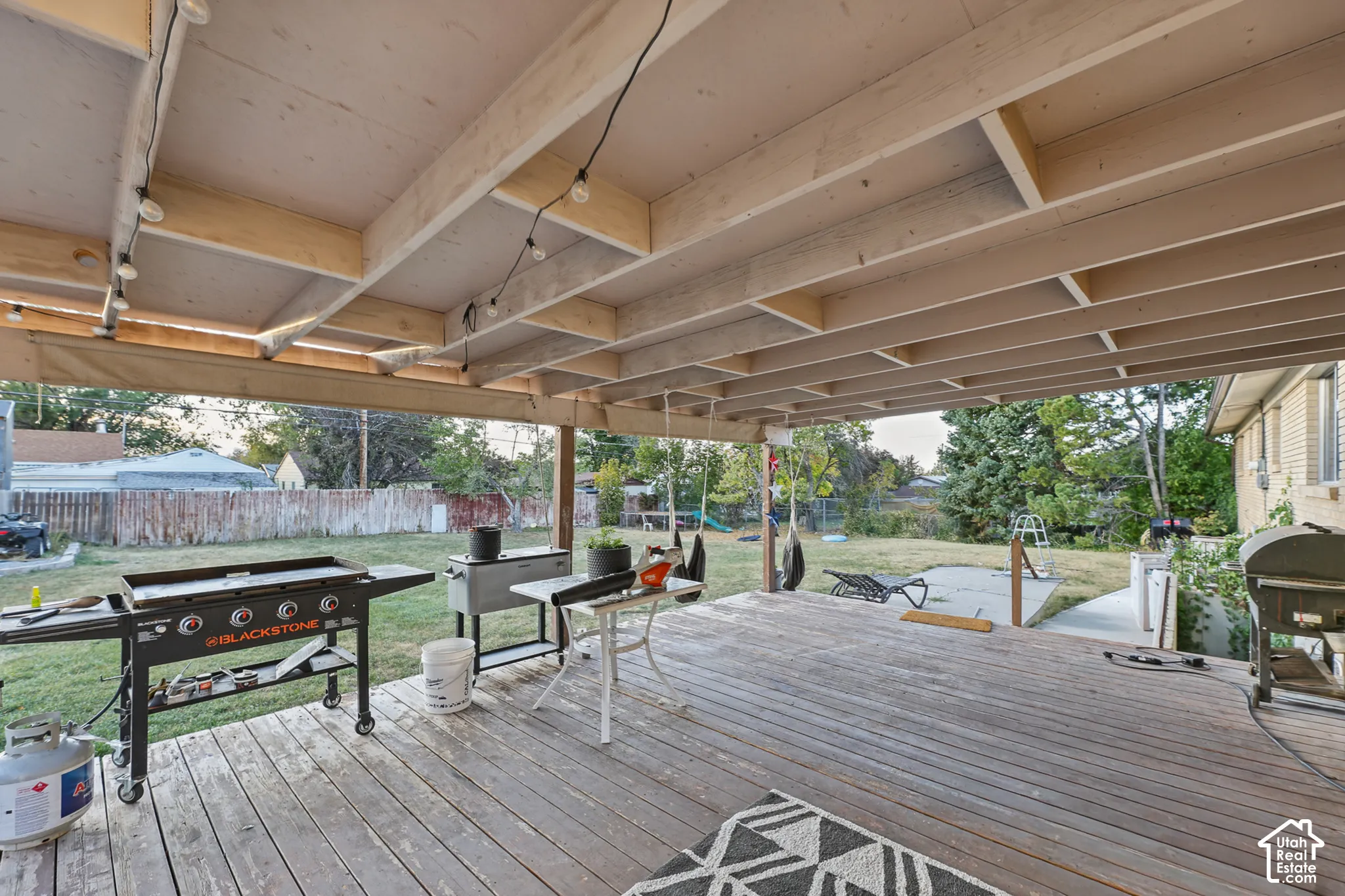 Expansive covered deck featuring string lighting and wood flooring