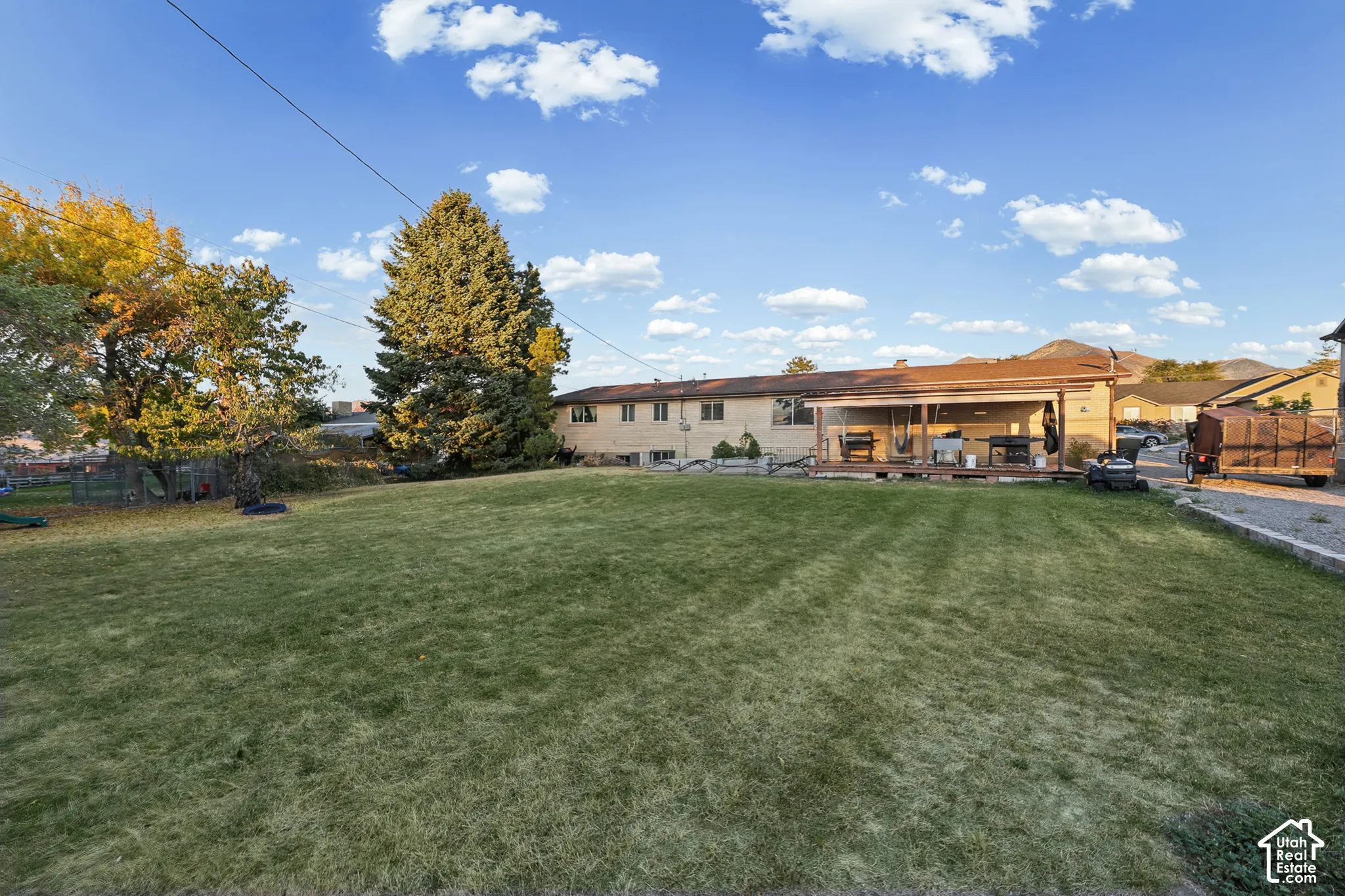 Expansive lawn area with a covered patio and mature trees