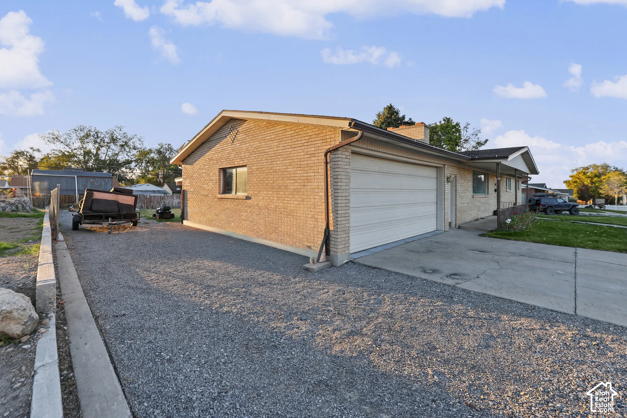 Single-story brick exterior, attached garage, and a gravel side yard