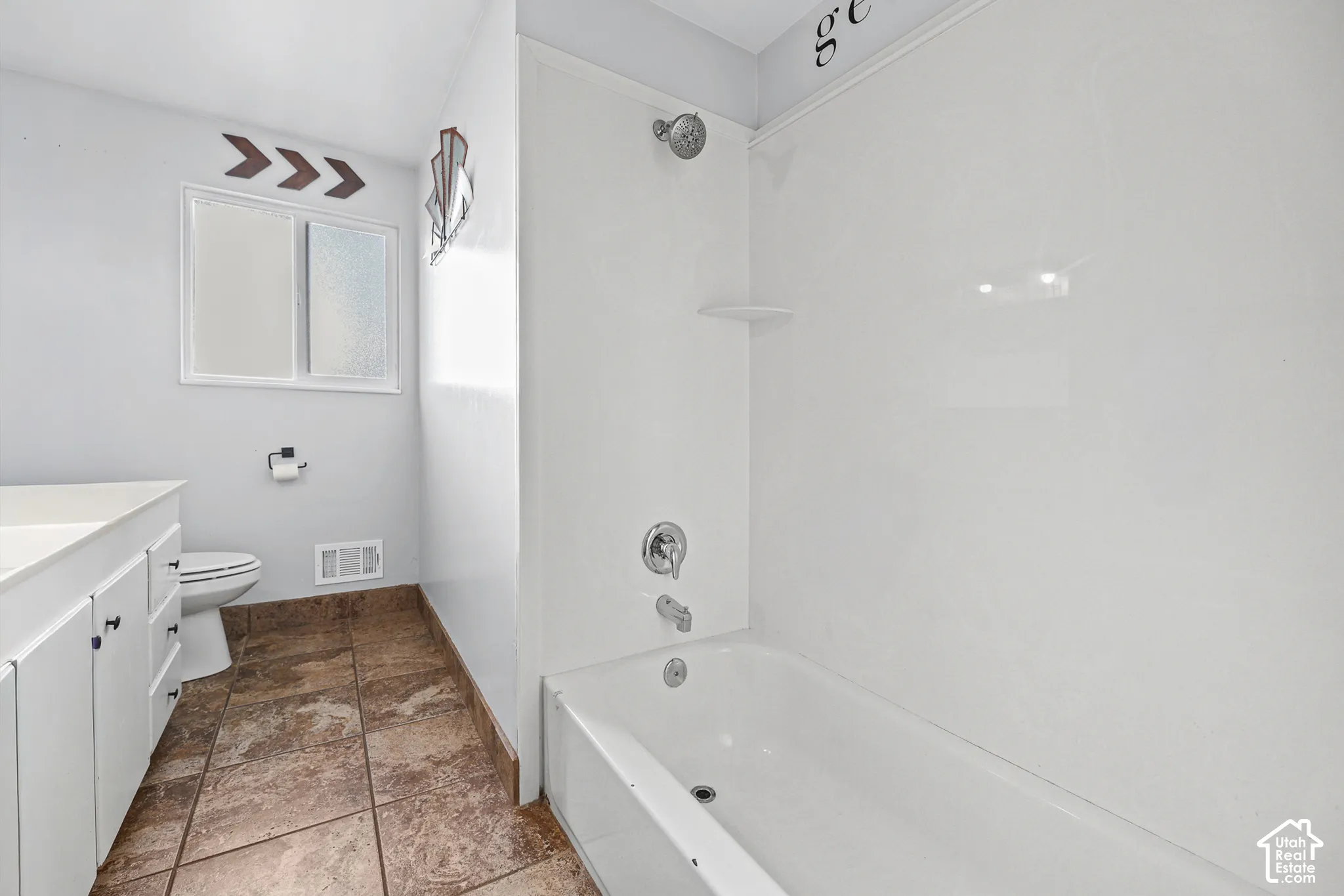 White vanity with dark hardware, white toilet, and a window with privacy glass