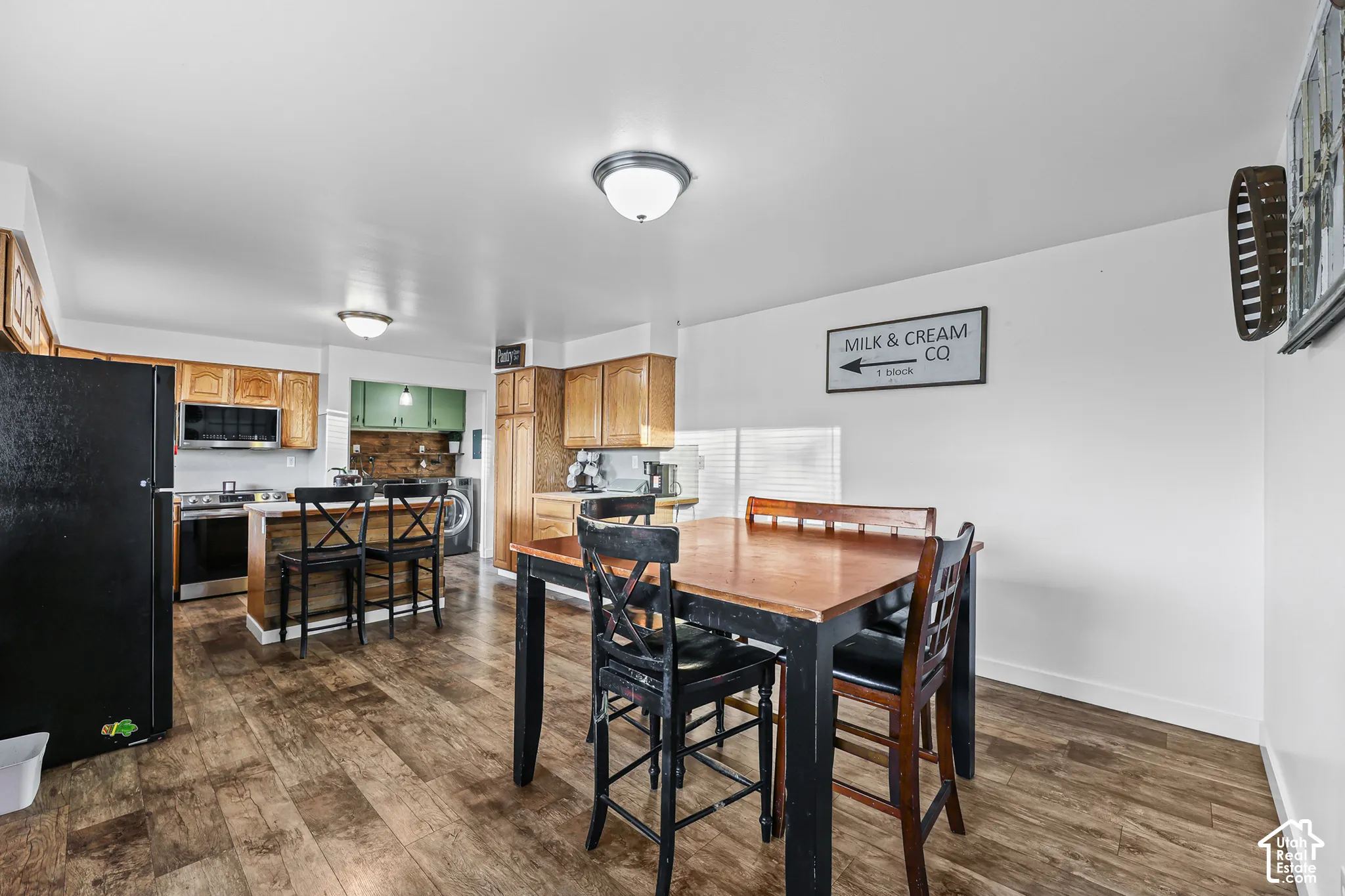 Open-concept kitchen and dining area featuring wood-finish flooring, recessed lighting, wood cabinetry, and a kitchen island with seating