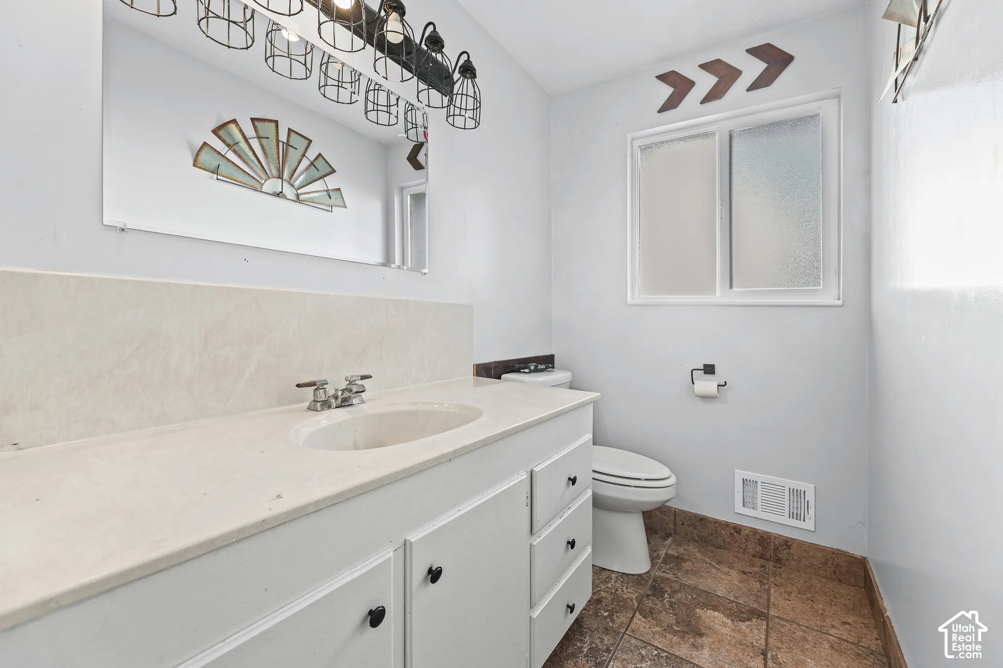 White vanity with an integrated sink and light-toned countertop, complemented by a large wall mirror