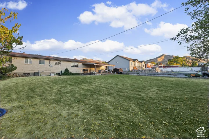 Expansive backyard with a manicured lawn, complemented by a covered patio and a brick exterior