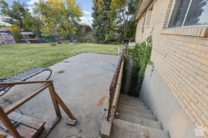 Expansive rear yard with a manicured lawn, concrete patio, and a dedicated concrete staircase access